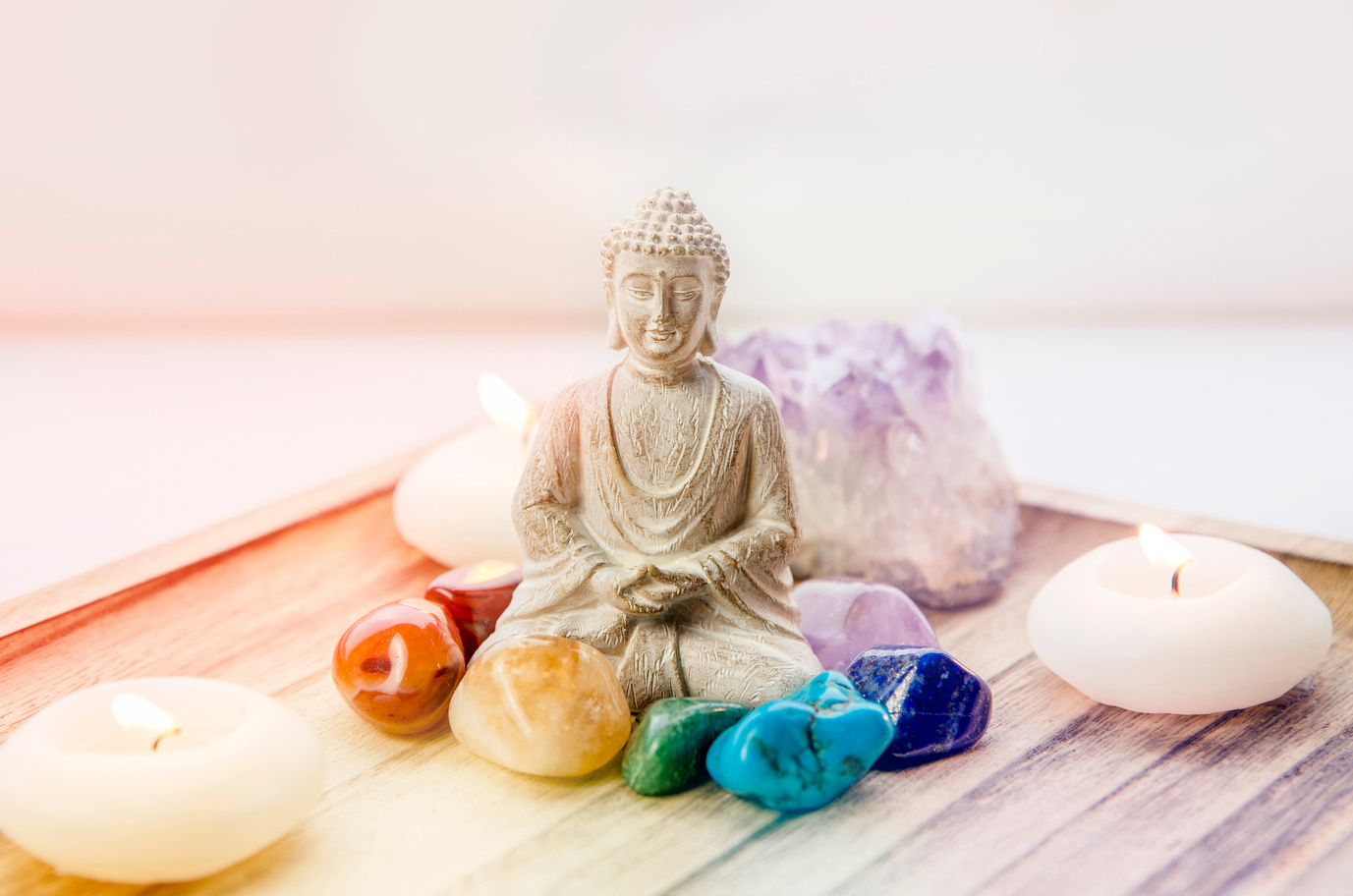 Seven chakra colors crystals stones around sitting Buddha.